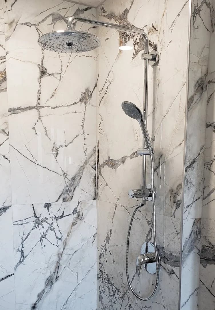 Chrome rain shower and handheld on marble-look tile