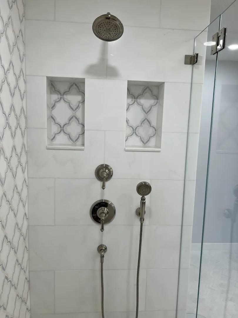 Walk-in shower with marble-look tile, mosaic niches, and dual shower heads